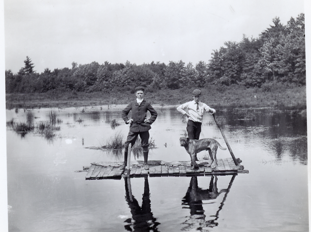 Two Men and a dog on a raft in the water