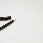 Uncapped black pen on a blank white background